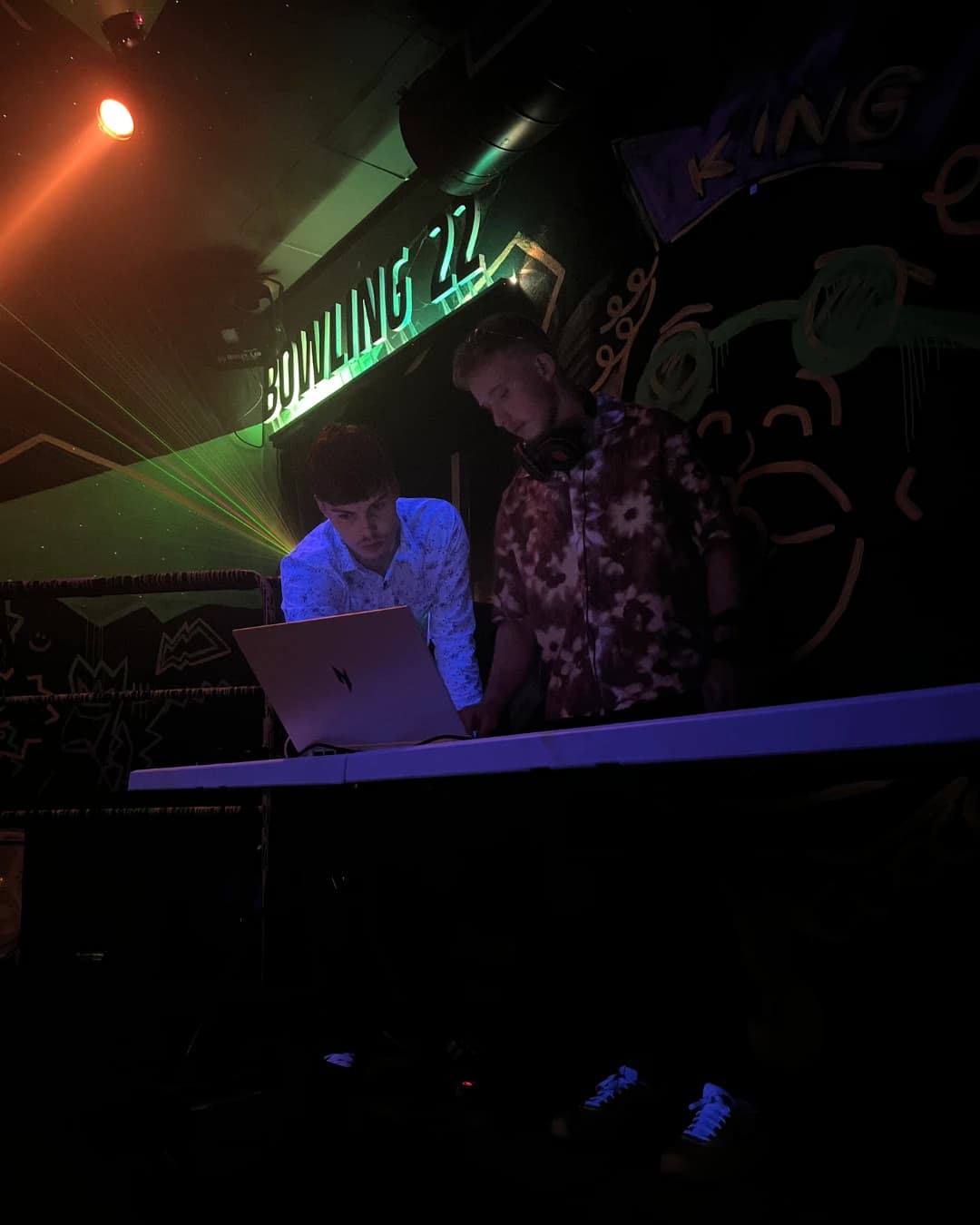 Vojtěch Bobek performing a DJ set in a club with stage lighting.